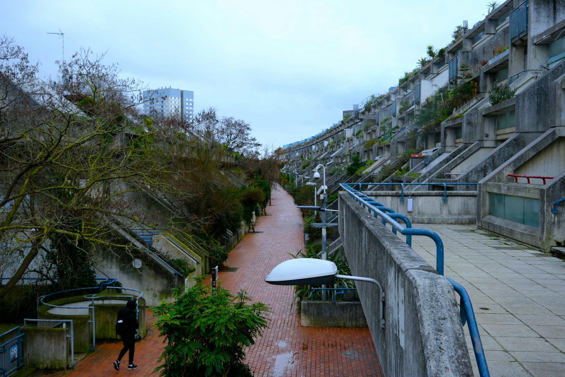 Weather, concrete and a passing figure create quiet narrative tension.